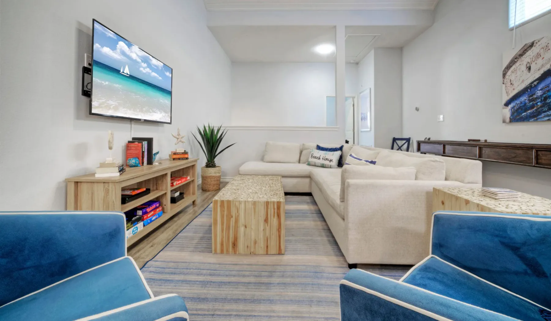 Una sala luminosa con asientos crema, sillones azules y una mesa de centro de madera.