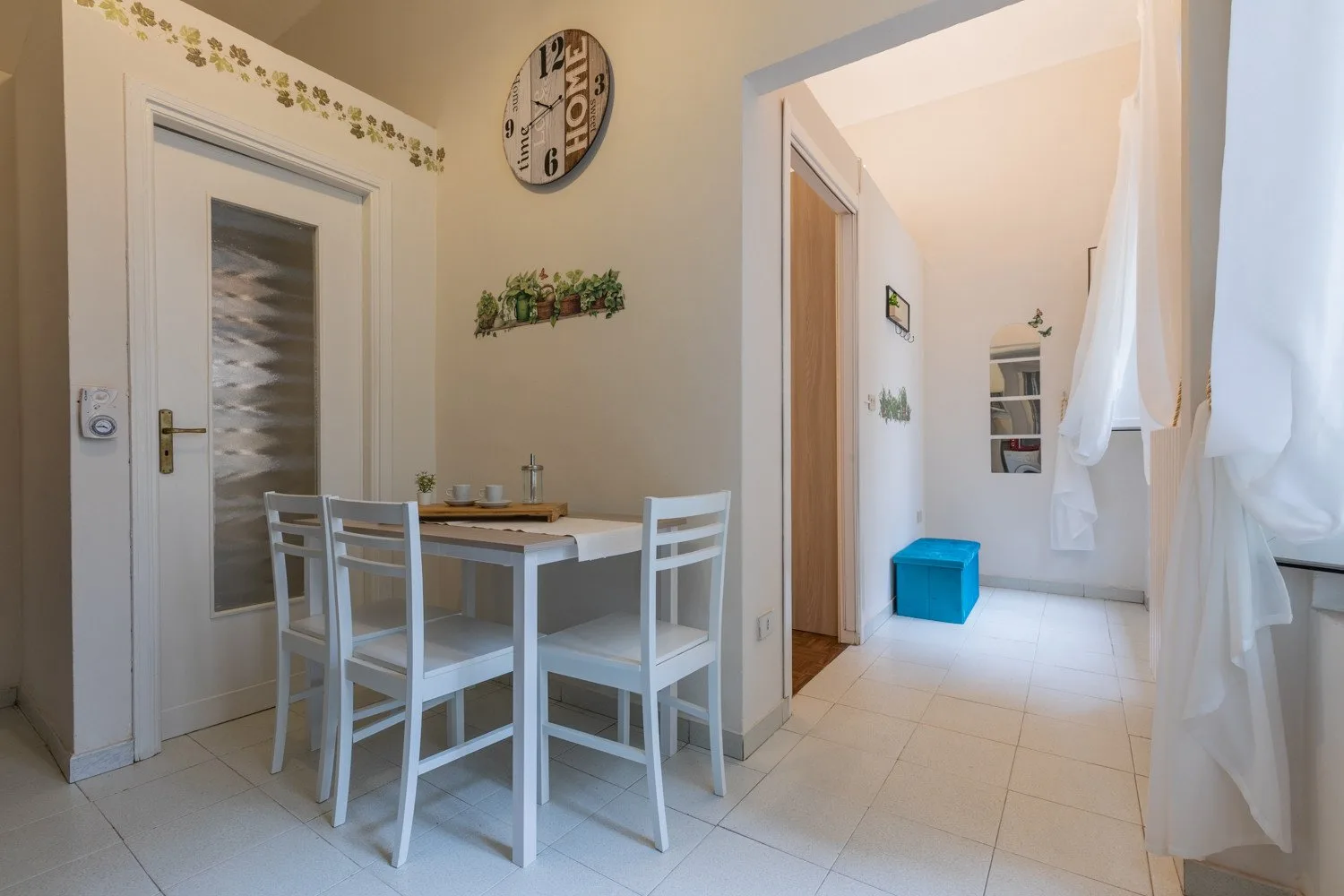 Un comedor con una mesa blanca y sillas junto a un pasillo luminoso.