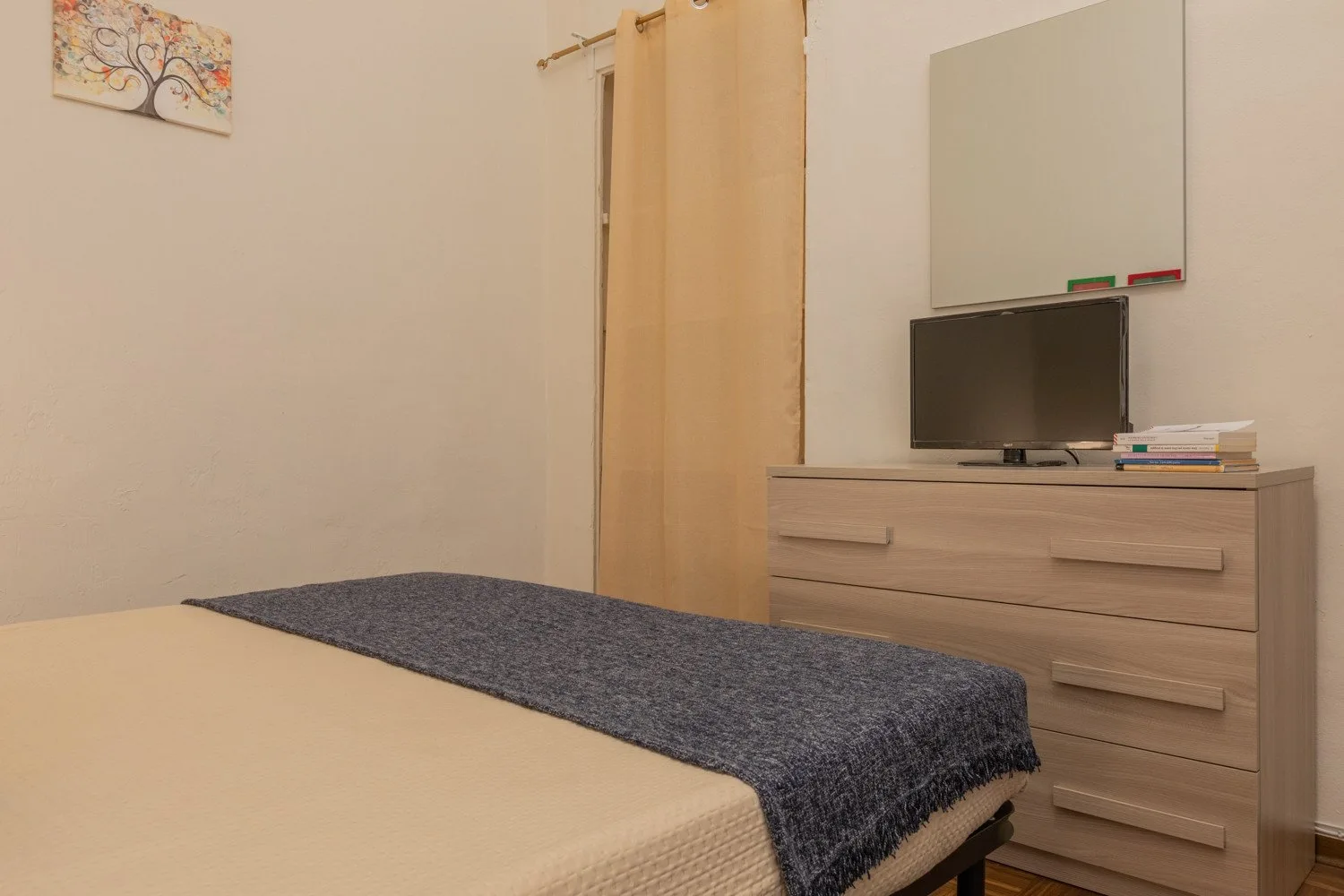 Un dormitorio con una cama, una cómoda y un televisor.