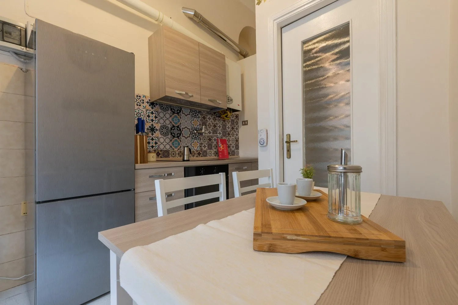 Una cocina compacta con zona de comedor y una mesa frente a los gabinetes.