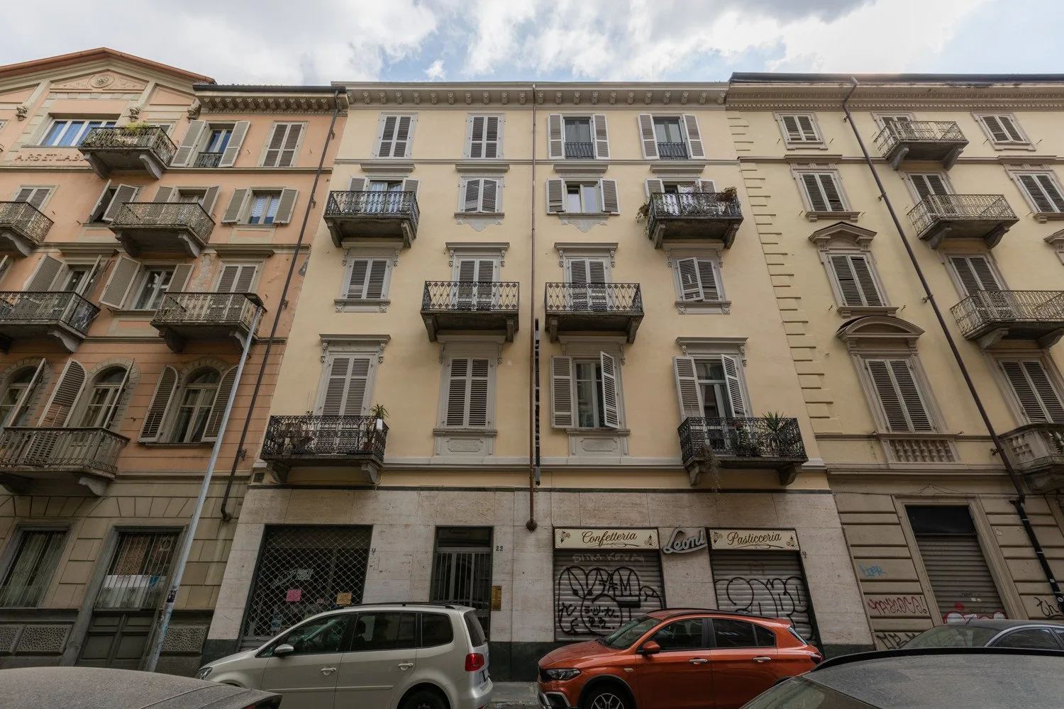 Vista de la calle de un edificio de varias plantas con balcones y locales en la planta baja.