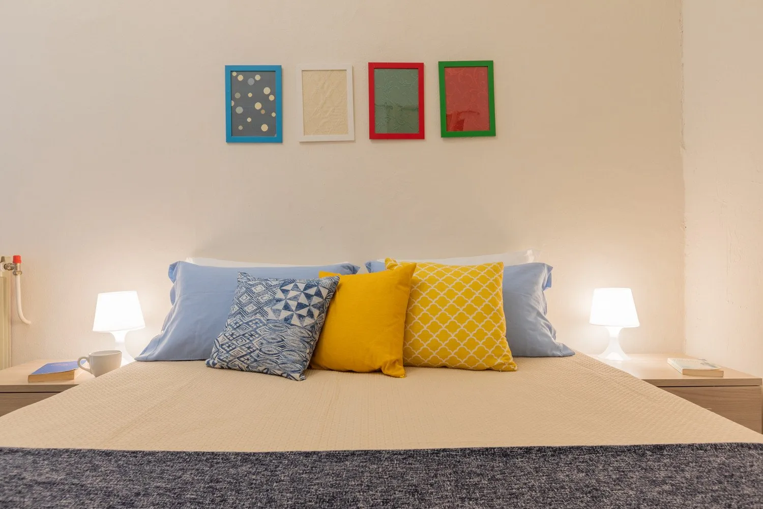 Dormitorio con una cama, cojines coloridos y cuadros en la pared.