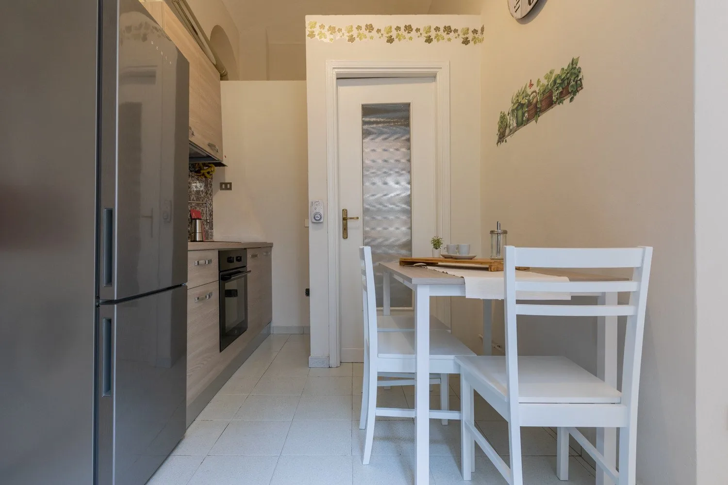 Una cocina compacta y zona de comedor con asientos blancos alrededor de una mesa.