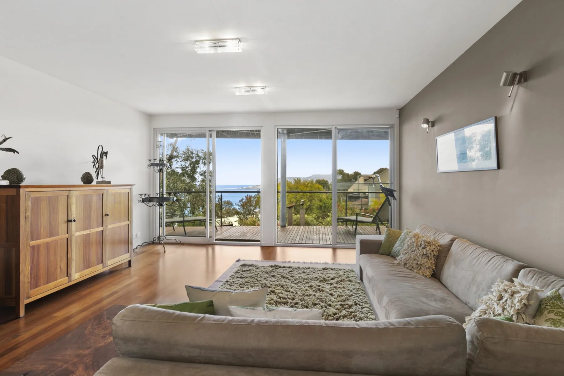 Living room with seating and large windows overlooking trees and water.