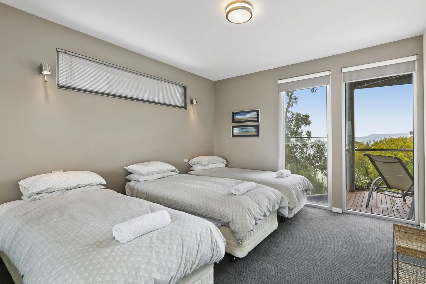 A bedroom with three beds and sliding glass doors opening onto a balcony.