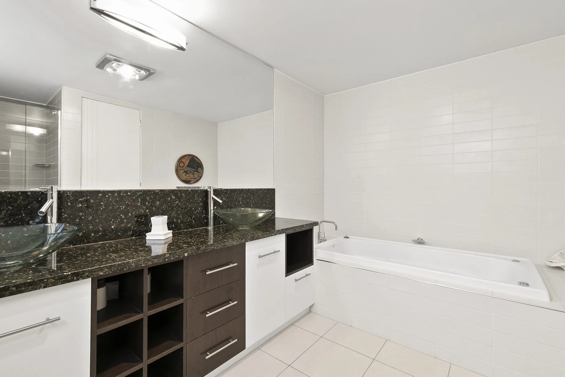 A bathroom with a bathtub, sink, and dark countertop.