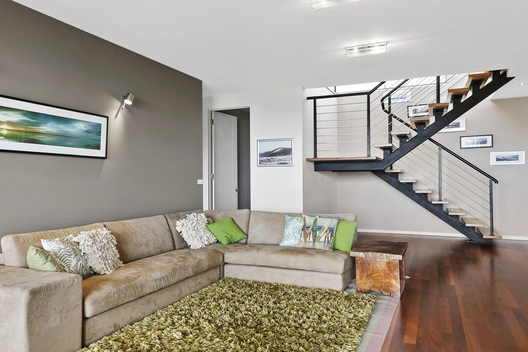 A living room with sectional seating and a staircase.
