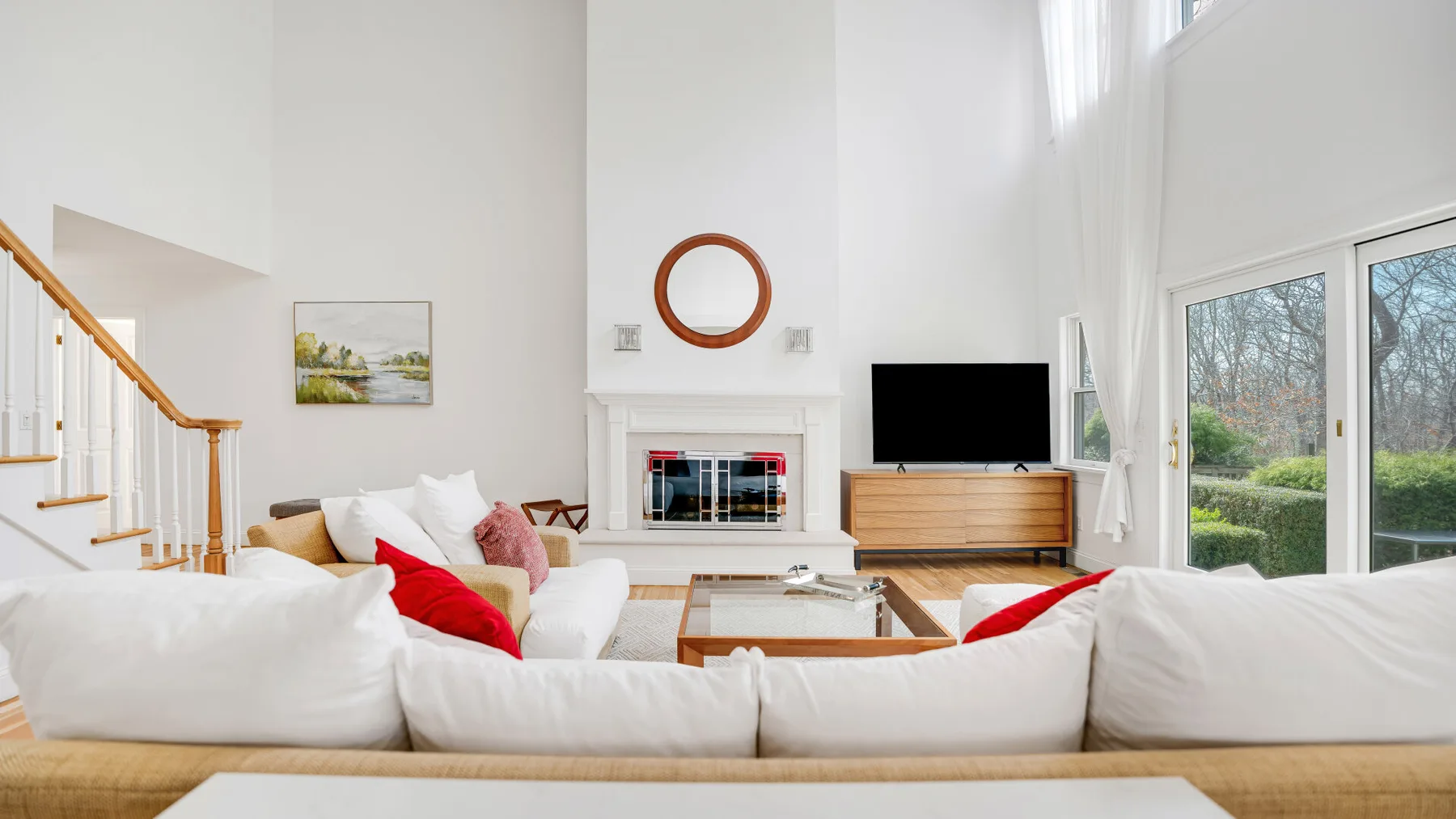 Una sala luminosa con asientos blancos, una chimenea y puertas de vidrio.