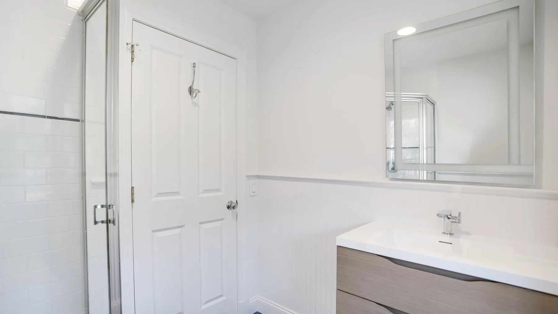 Un baño luminoso con un lavabo blanco y un espejo grande en la pared.