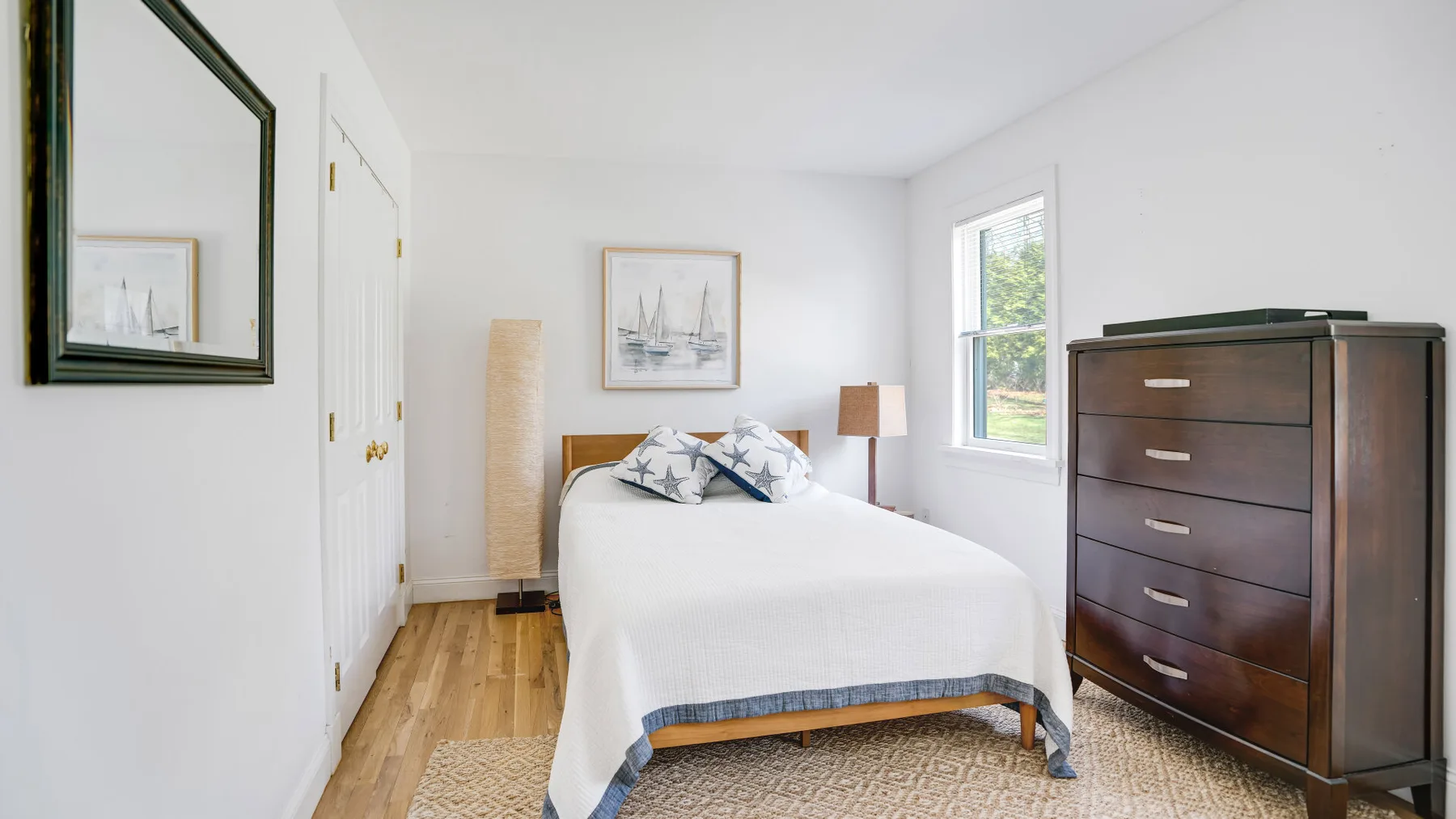 Un dormitorio luminoso con una cama tendida y una ventana.