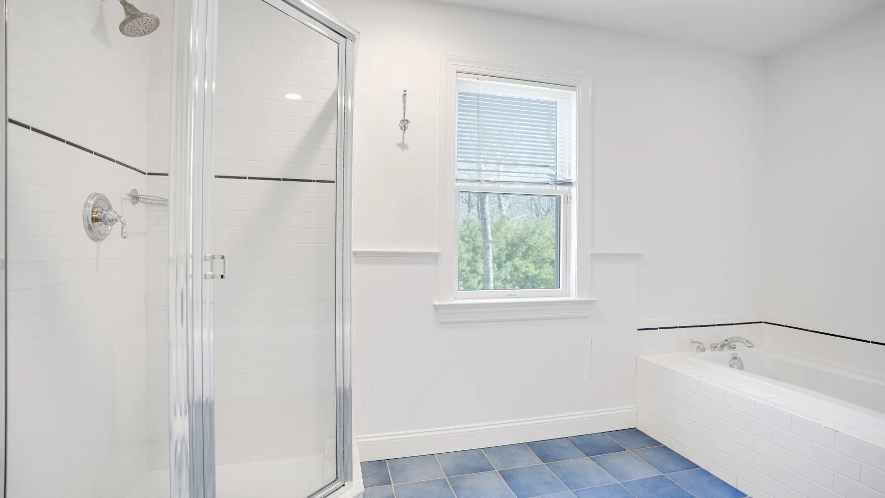 Un baño luminoso con ducha de vidrio, bañera y ventana.