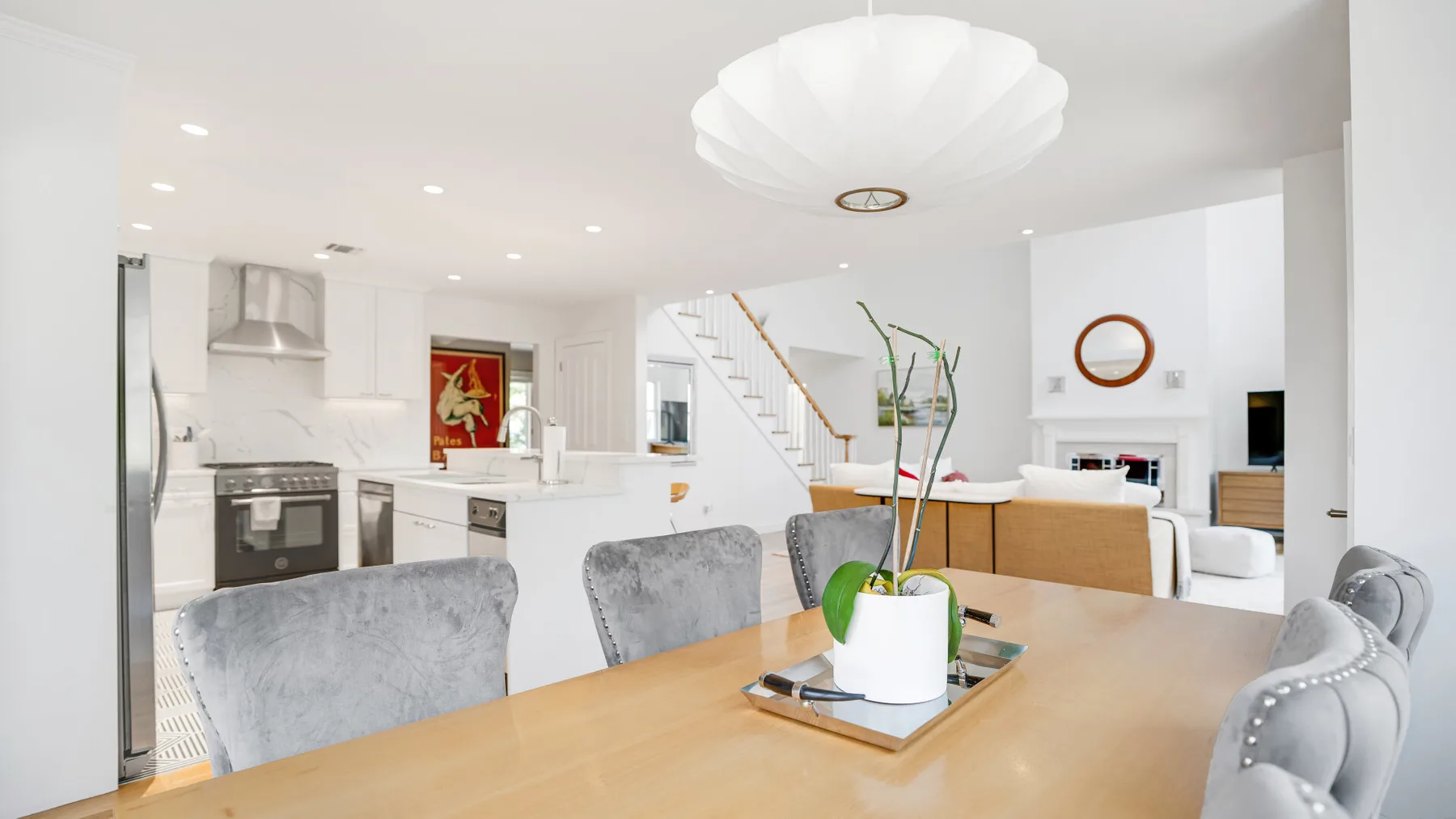 Una luminosa cocina y comedor de planta abierta, con una mesa de madera y gabinetes blancos.