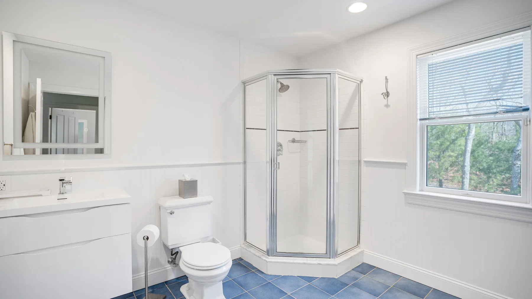 Un baño luminoso con ducha de vidrio, lavabo y ventana.