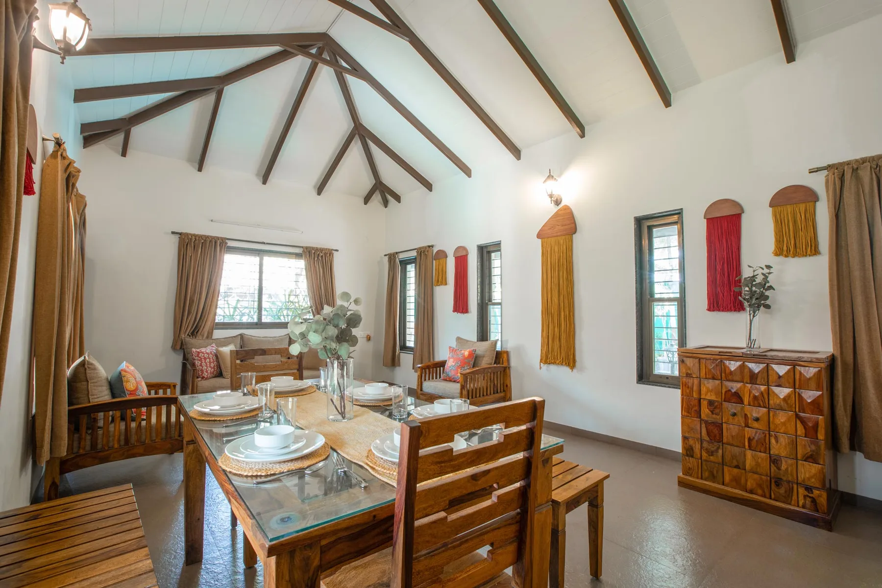 Un comedor y sala de estar luminosos con una mesa de madera bajo vigas expuestas.