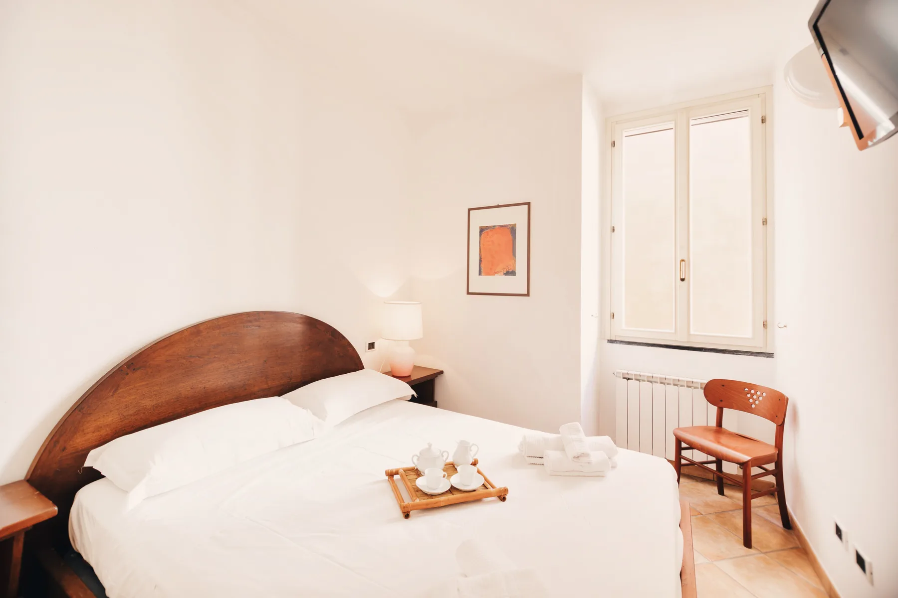 A bright bedroom with a neatly made bed and a window.