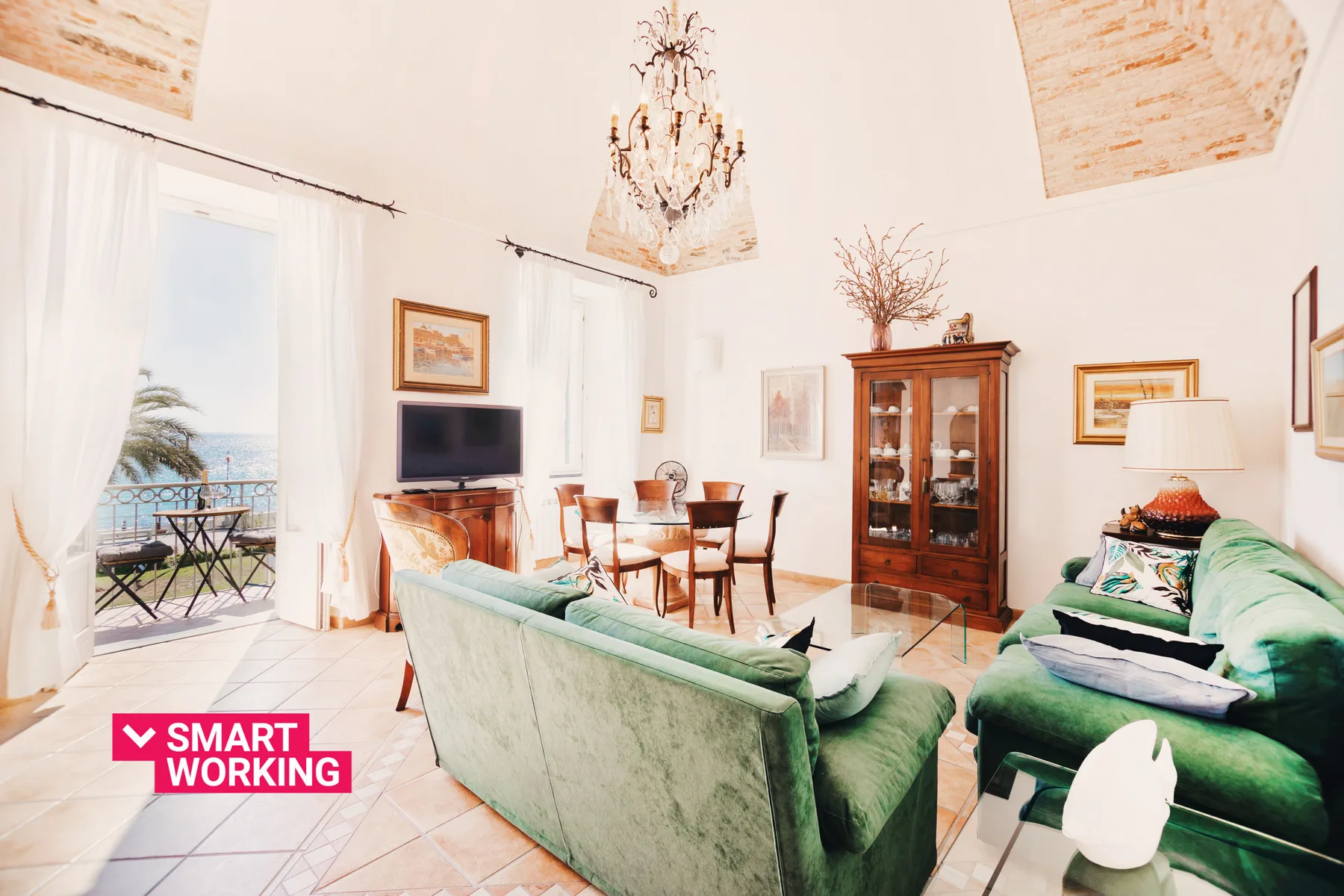 A bright living and dining room with green seating and a wooden dining table.
