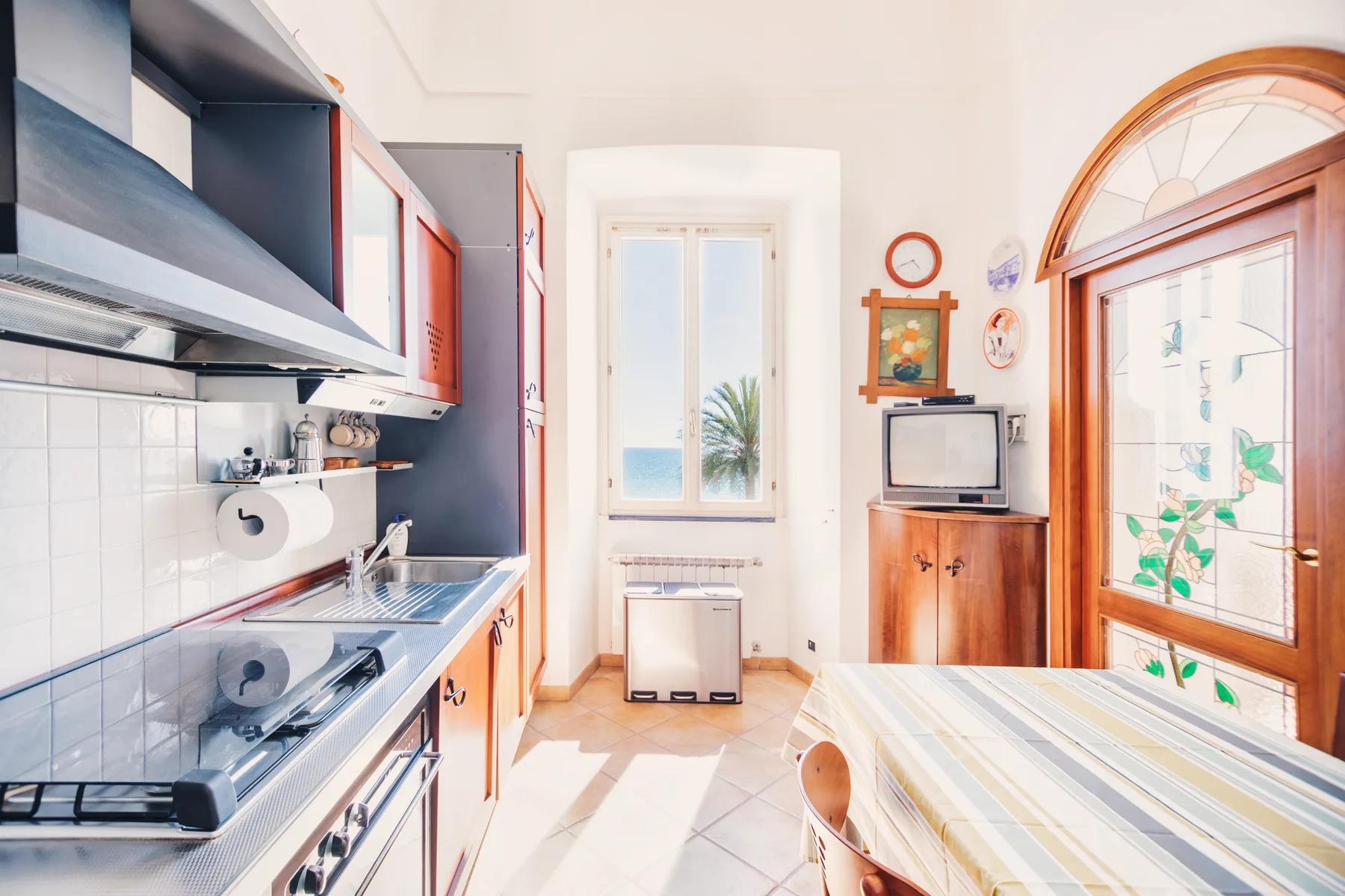 A bright kitchen with a tiled counter and a small table beside the window.