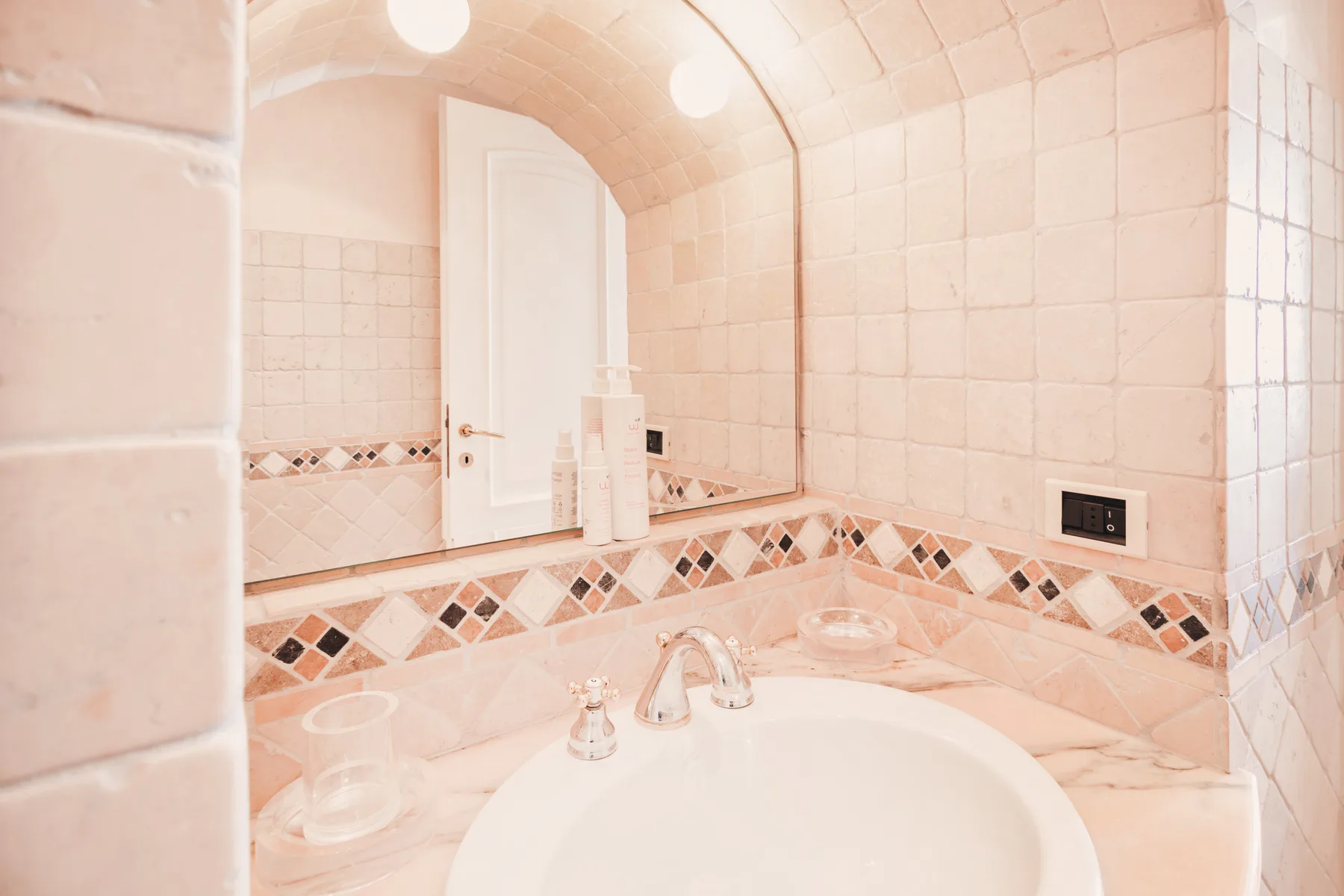 A tiled bathroom vanity with a large mirror and curved sink.