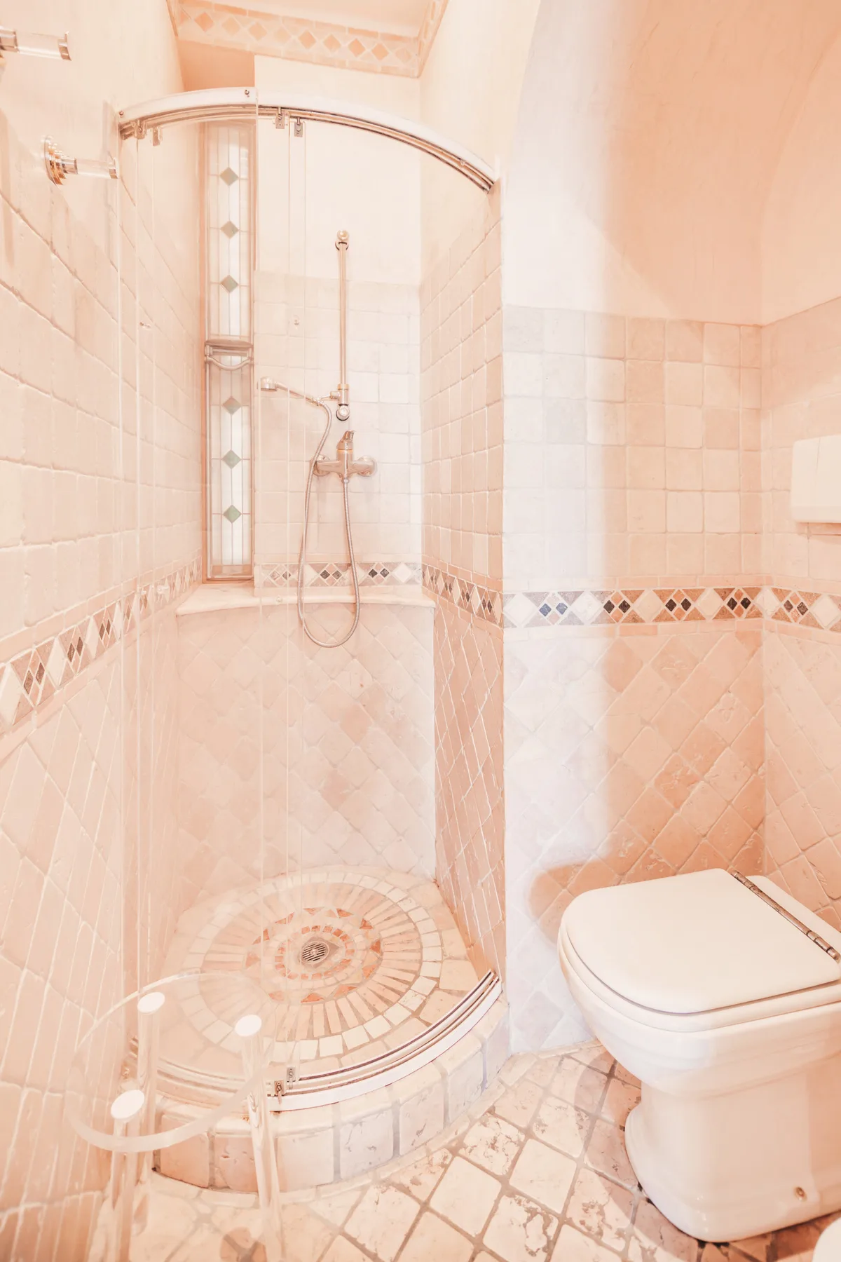 A tiled bathroom with a curved glass shower enclosure and a toilet.