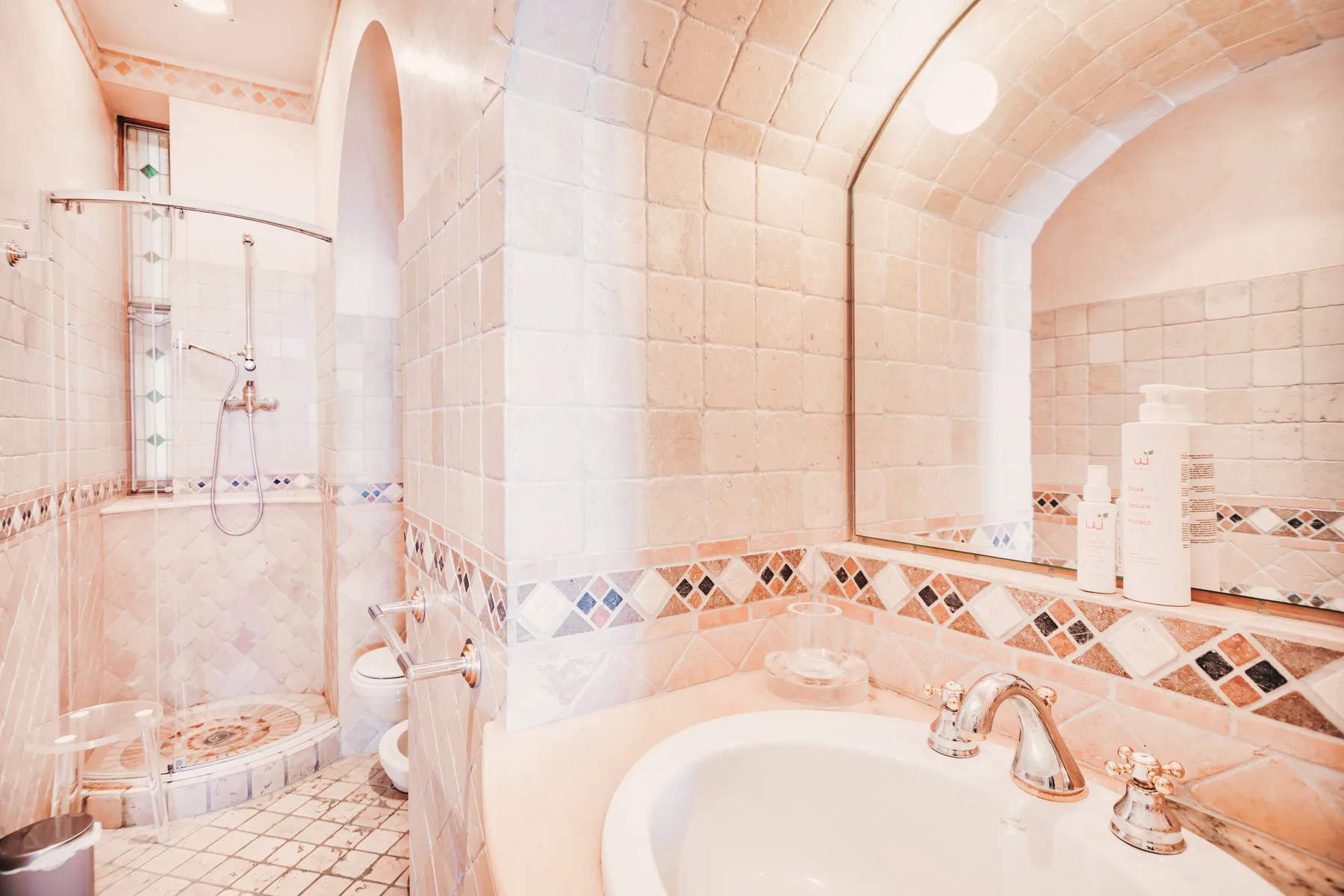 A tiled bathroom with a bathtub, sink, and glass shower.