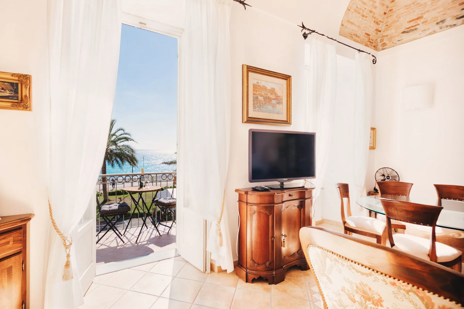 A bright dining room opens onto a balcony with a sea view.
