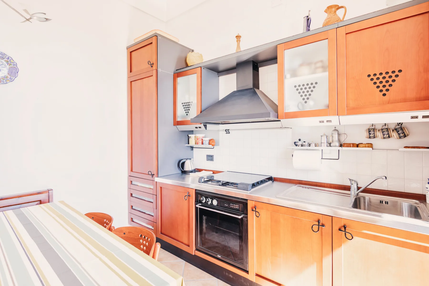 A bright kitchen with wooden cabinets, a stove, and a sink.