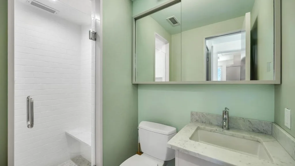 Un baño con ducha acristalada, lavabo y armario con espejo.
