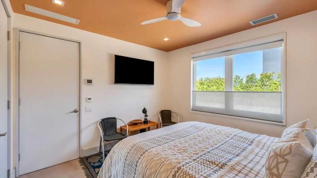 Un dormitorio con cama, televisor y una ventana grande.