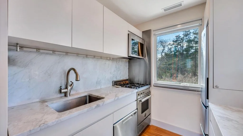 Una cocina luminosa con encimera, fregadero y una ventana grande.