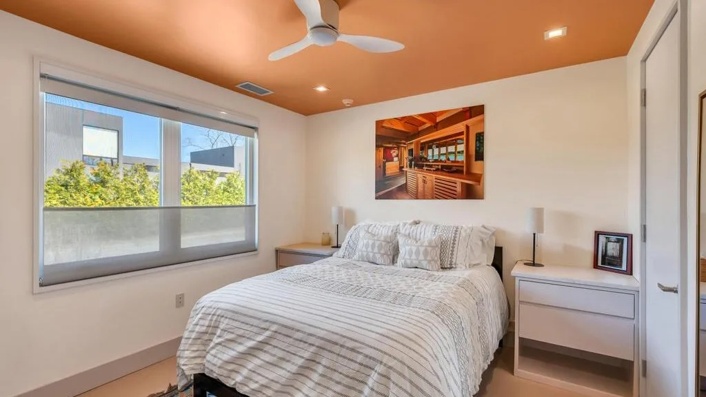 Un dormitorio con una cama, mesas de noche y una ventana grande.