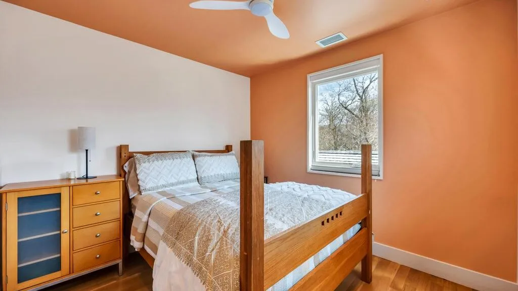 Un dormitorio con una cama de madera, una cómoda y una ventana.