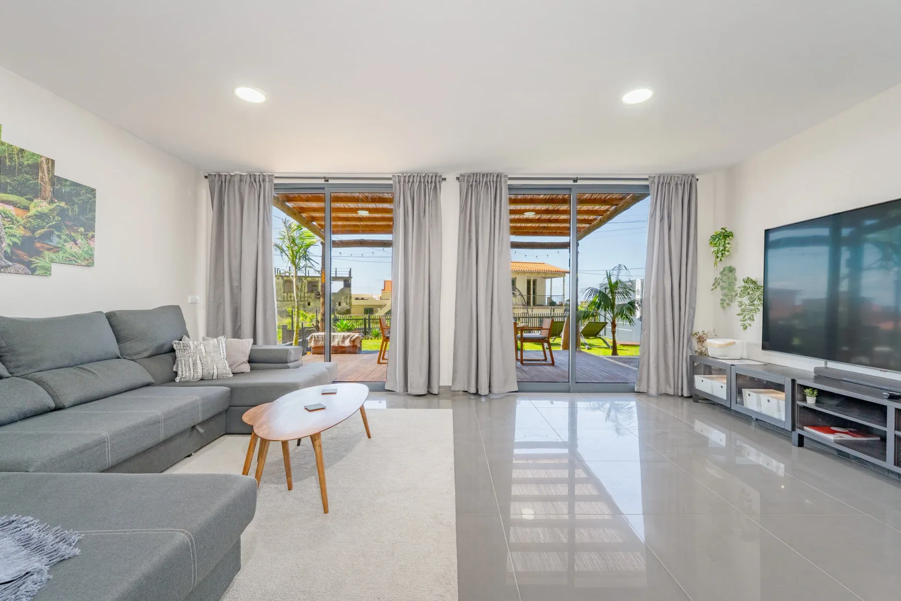 Living room with sofas, coffee table, television, and glass doors to the patio.