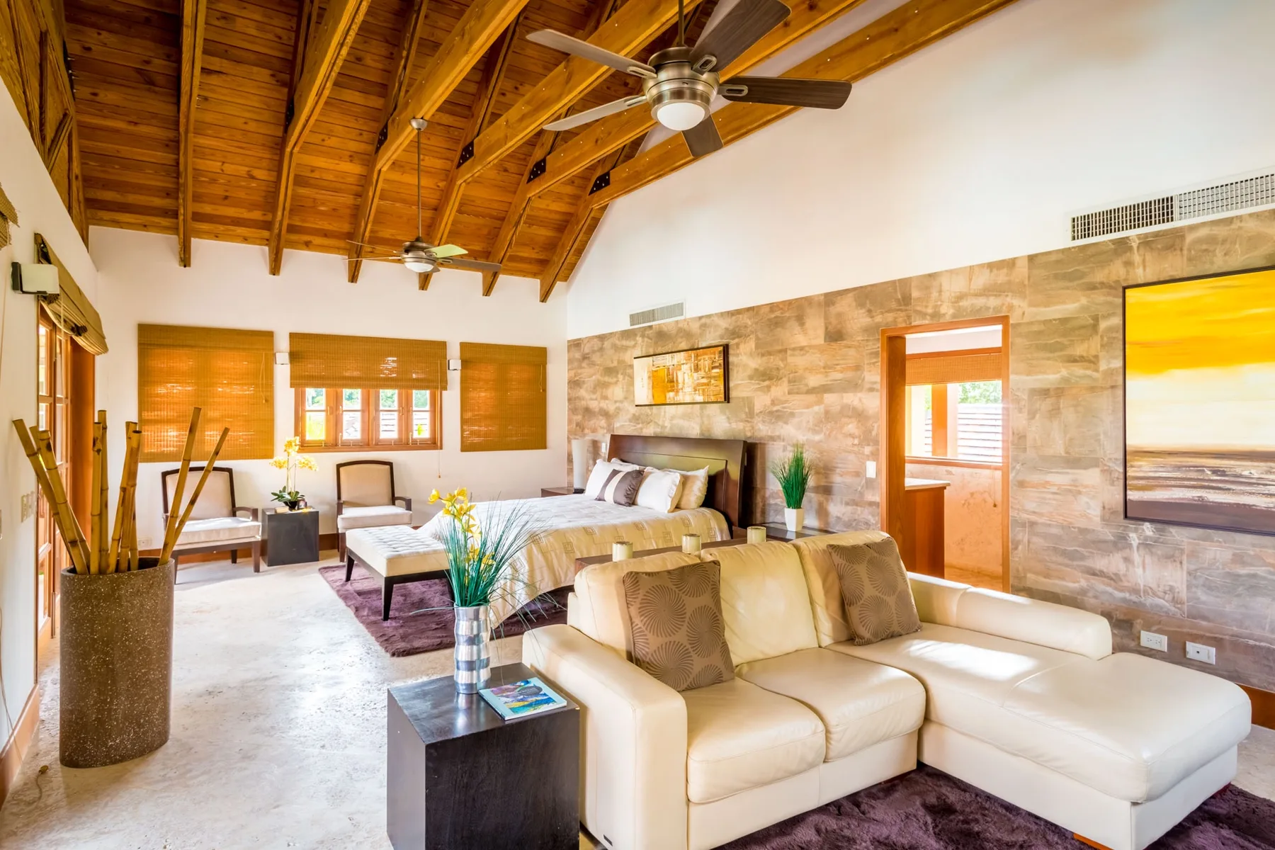 A bright living room with pale seating and exposed wooden ceiling beams.