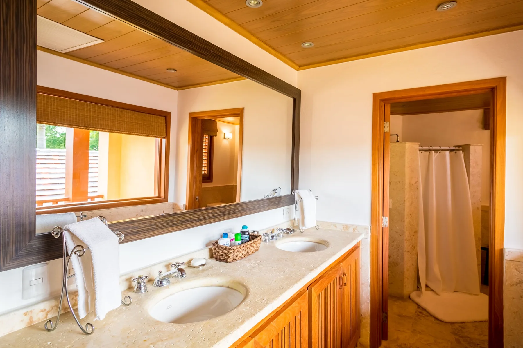 A bathroom vanity with two sinks faces a curtained shower.
