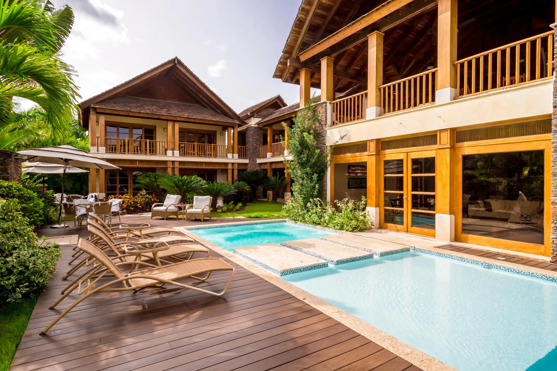 An outdoor pool beside a wooden deck and a large timber-framed building.
