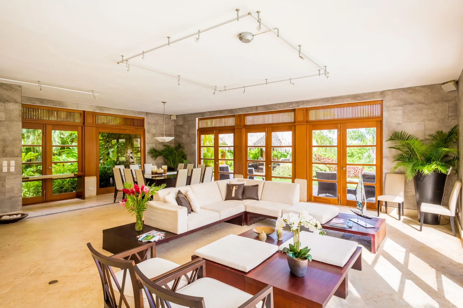 A bright living room with lounge seating and large wood-framed windows.