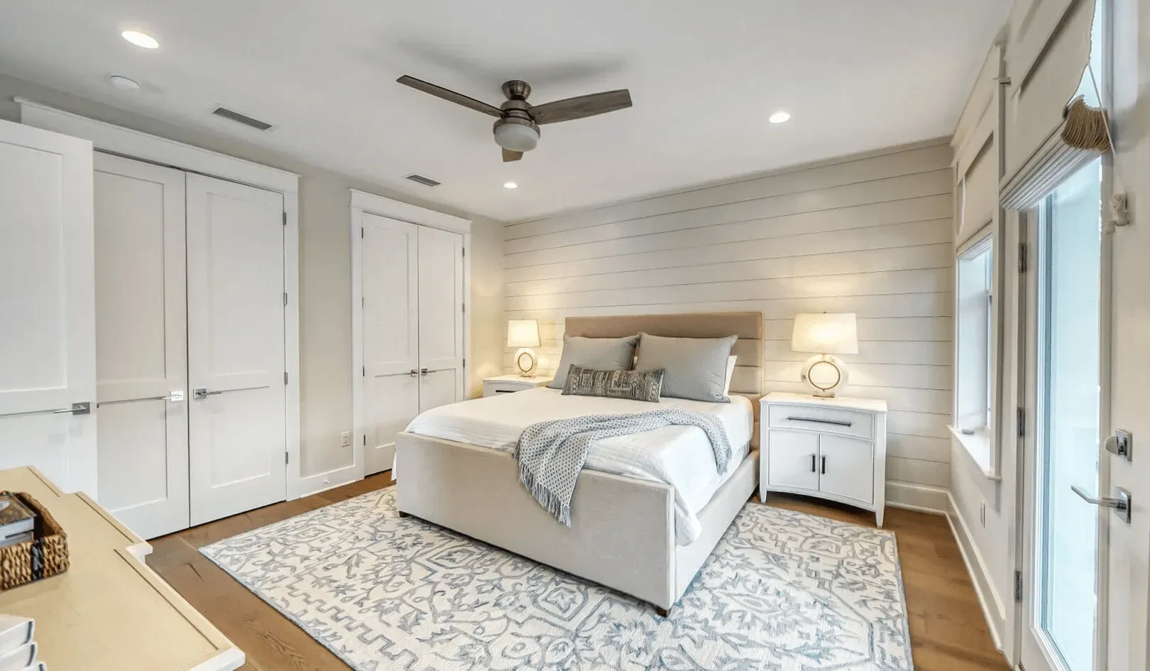 A bedroom with a bed, bedside tables, and a patterned rug.
