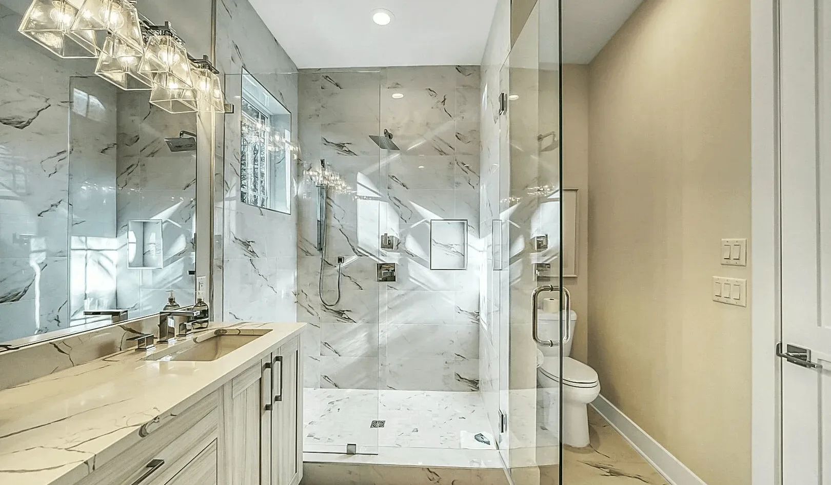 A bright bathroom with a glass shower and a long vanity.