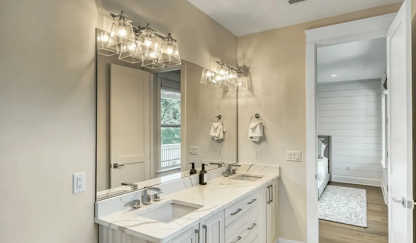 A bright bathroom vanity with a wide mirror and two sinks.