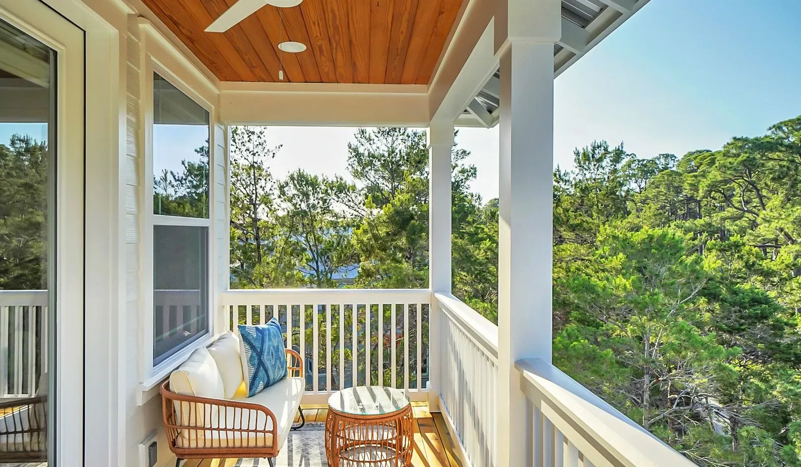 A covered balcony with seating overlooks a green, tree-covered landscape.
