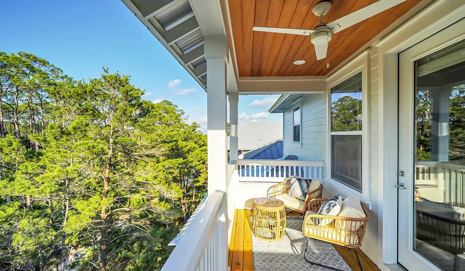A covered balcony with seating overlooks a wooded landscape.