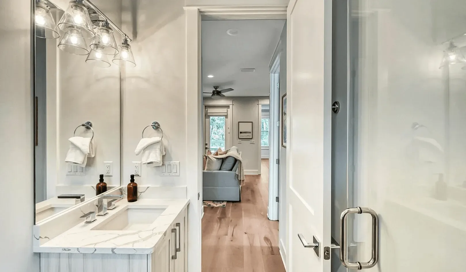 A bathroom vanity with a large mirror opens onto a hallway and sitting area.