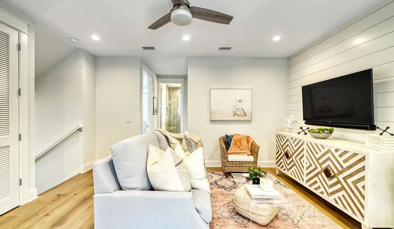 A bright living room with a sofa, coffee table, and wall-mounted television.
