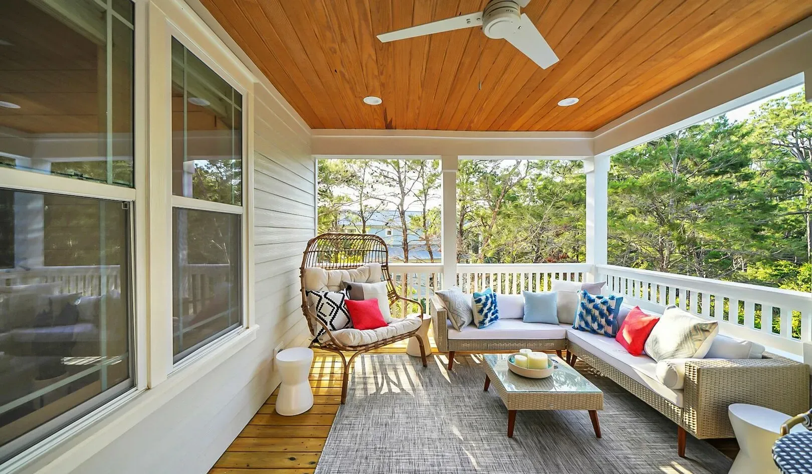 A covered porch with a cushioned seating area and a ceiling fan.