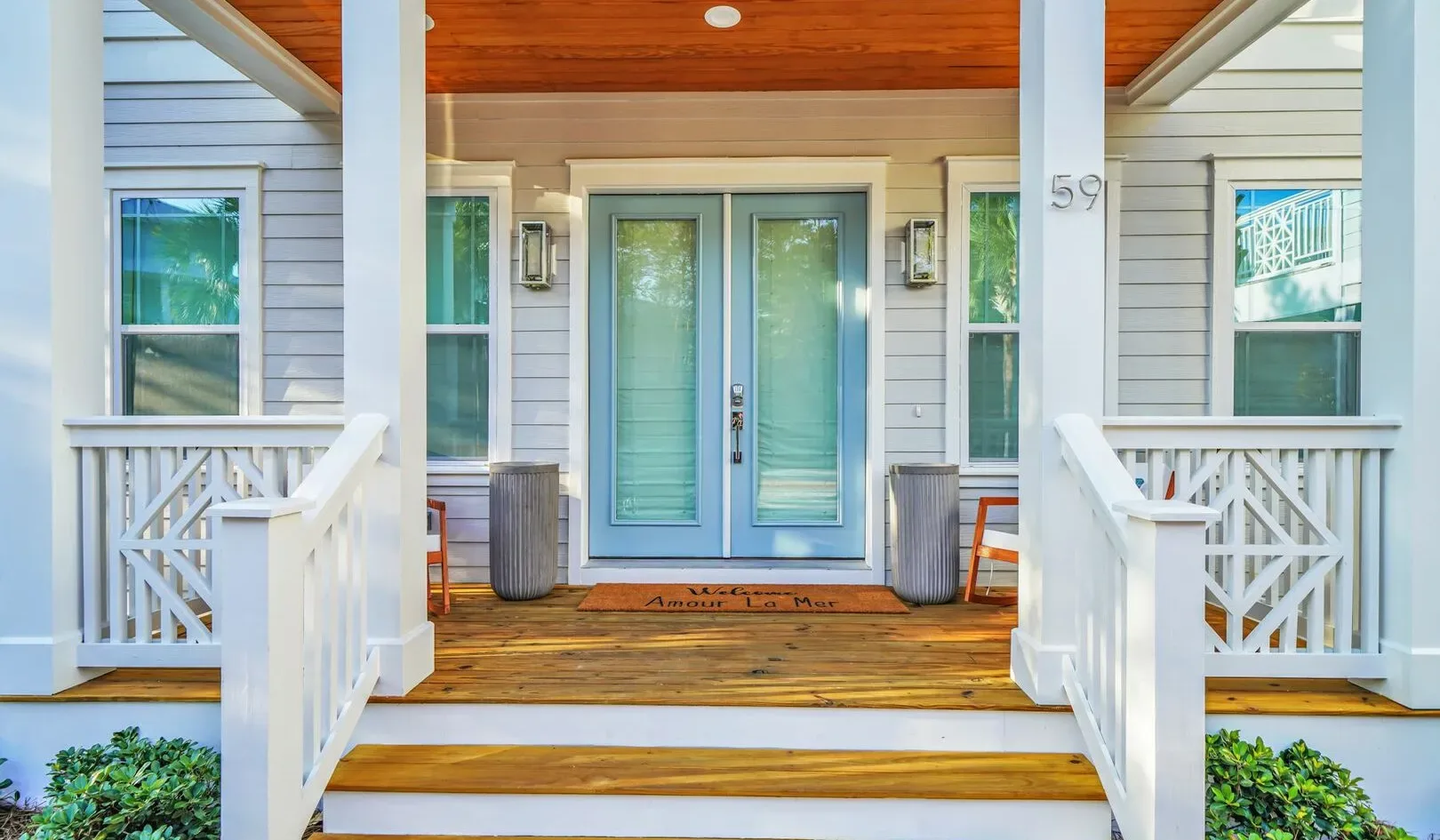 A covered porch with a central glass entry door and white railings.
