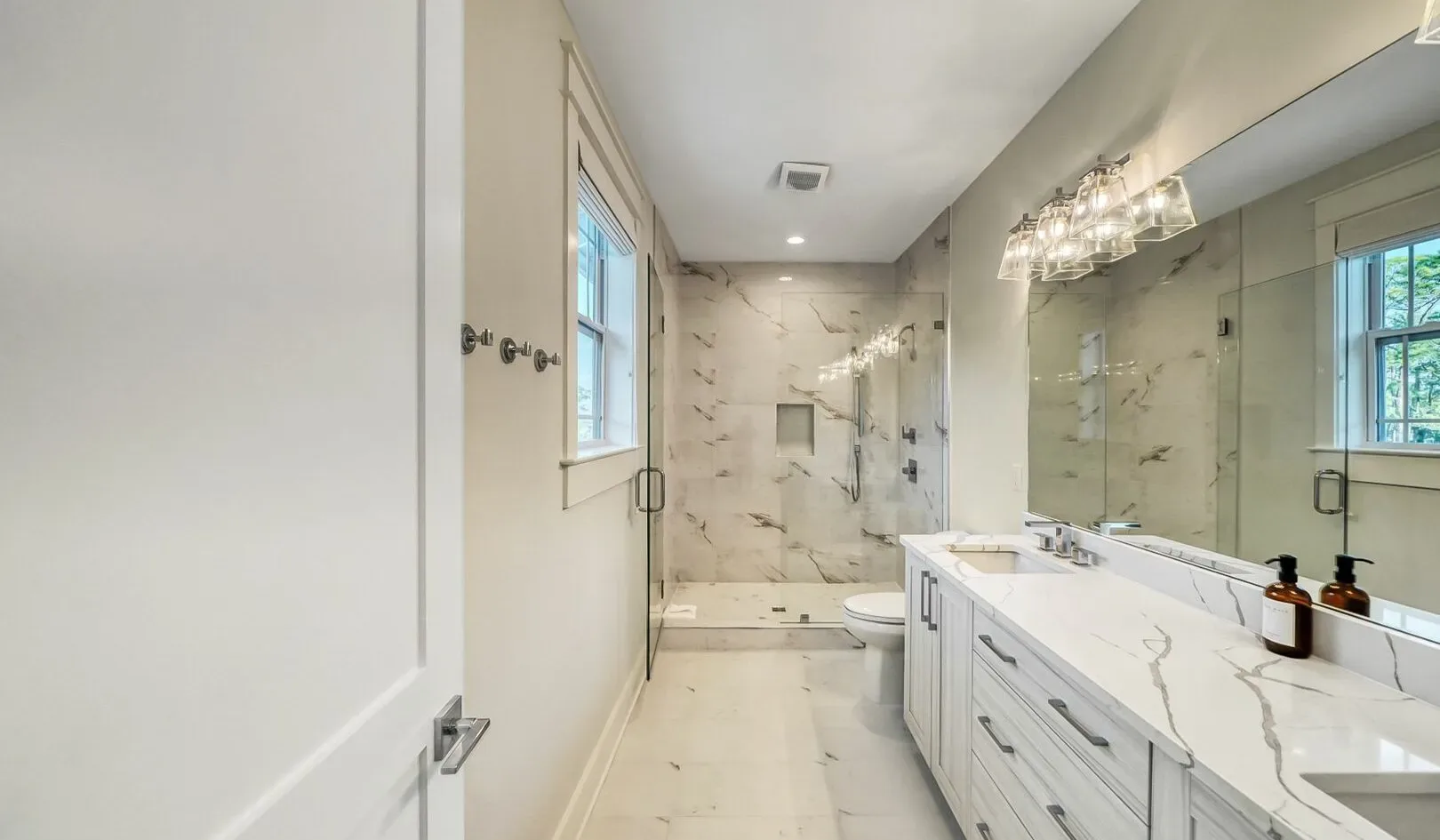 A bright bathroom with a long vanity and a glass shower.