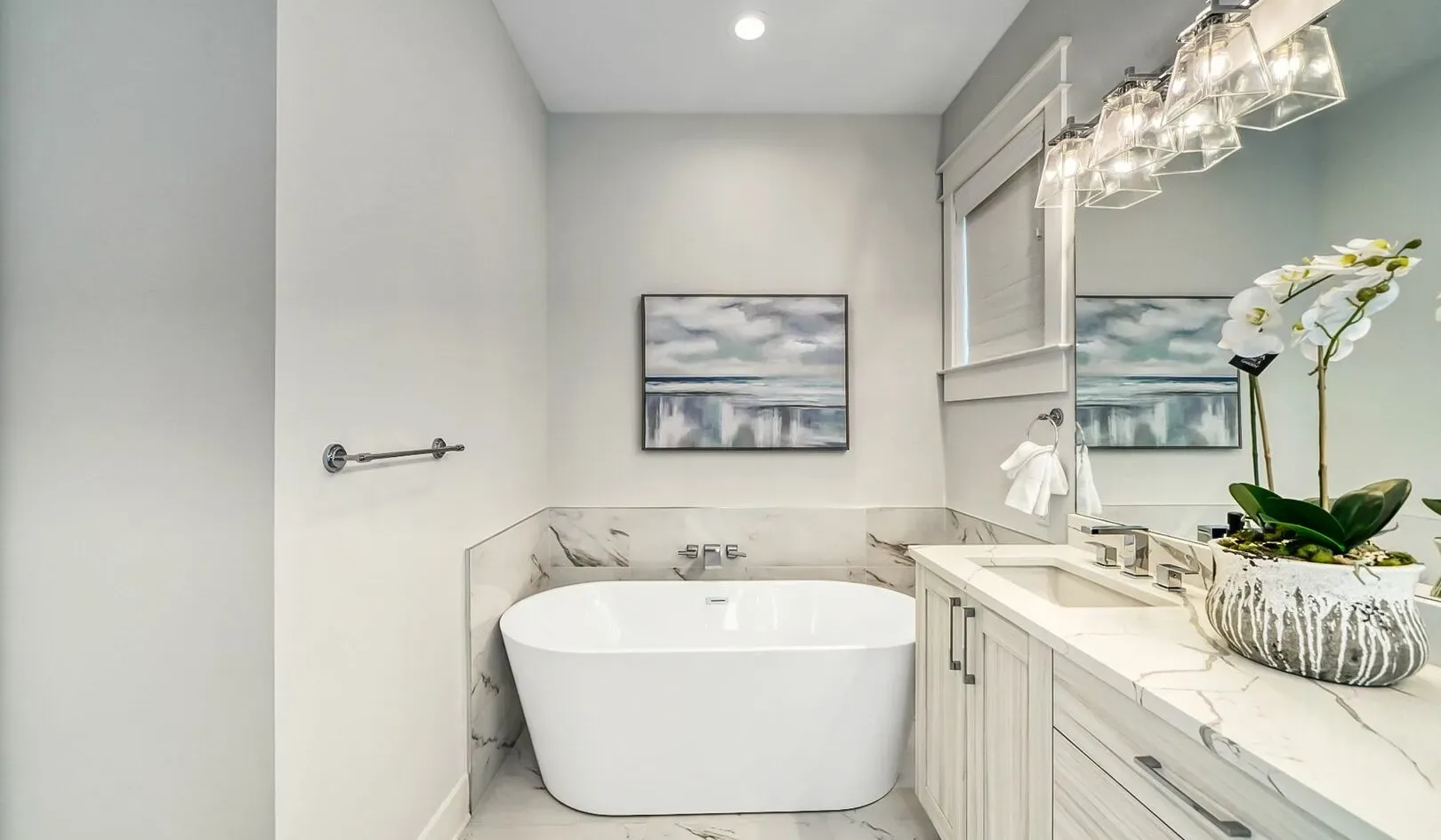 A bright bathroom with a freestanding bathtub and a long vanity.