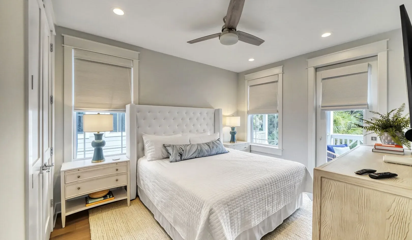 A bright bedroom with a neatly made bed and windows.