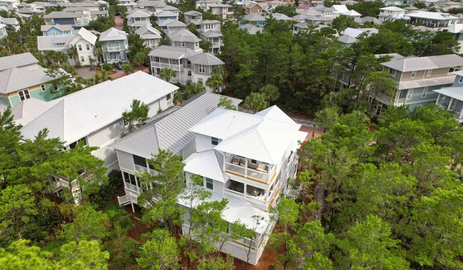 An aerial view of houses surrounded by dense green trees.