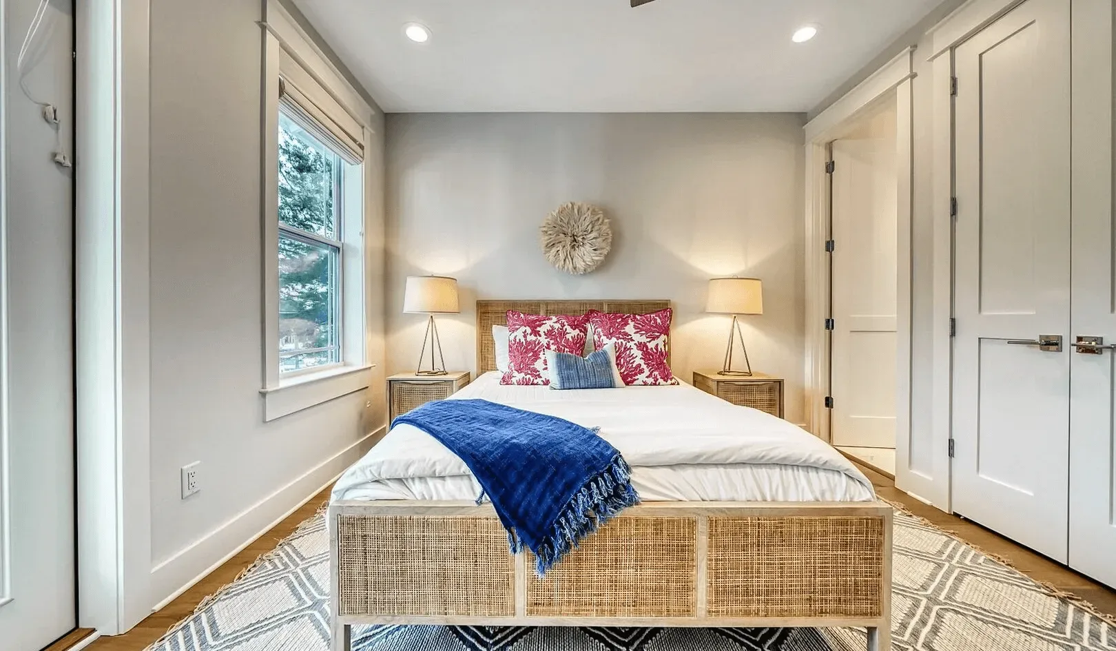 A bedroom with a bed, bedside lamps, and built-in cabinets.